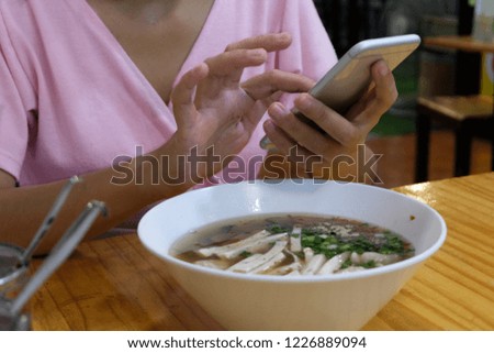 woman's hands holding mobile phone in restaurant.