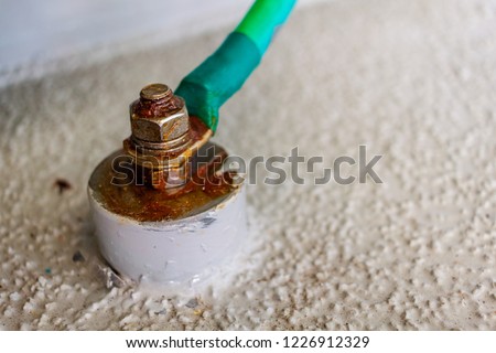 Green electrical ground wires is connected to ground copper terminal bar or earth bonding terminal bar in electrical device with electrical grounding sign near ground bolt for safety system. Royalty-Free Stock Photo #1226912329
