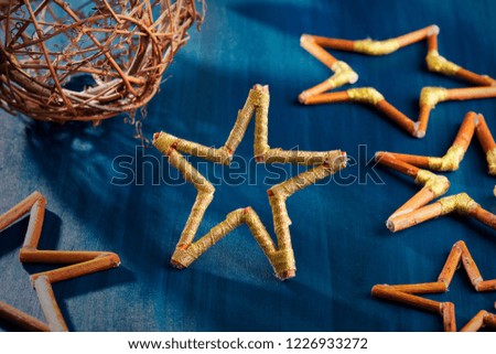 Handmade Christmas decoration made of natural materials and golden ribbon on a blue, wooden desktop.