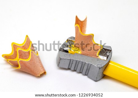 Color pencil and prism sharpener with chip macro photo on white background. Sharpening pencil concept. Creative and intellectual development. Yellow crayon preparing for art work. Art supply closeup
