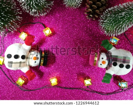 Lovely Snowman flat lay on pink gliter background near ornament lighting bulb at silent night, holy night, Merry Christmas and happy new year.