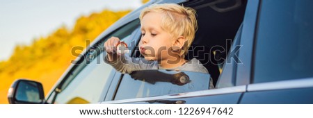 Boy blowing bubbles in the car window. Traveling by car with children BANNER, LONG FORMAT