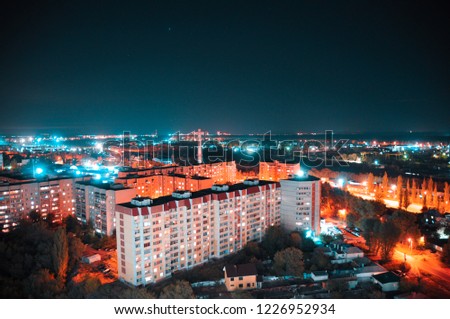 Bird's-eye view of the night city with the luminous lights  of lanterns and windows of the houses
