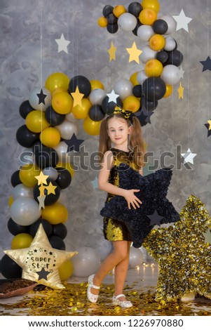 Movie super star girl model posing in studio shoot with golden star and colorful baloons wearing stylish gold airy dress with shining bow tie.Super star pillow deisigned by photographer