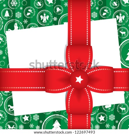 Beautiful decorative Christmas gift with a blank white card for your greeting wrapped in festive patterned green paper and tied with an ornamental red ribbon and bow