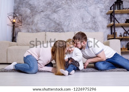 Parents are kissing her daughter. Happy family having fun time at home
