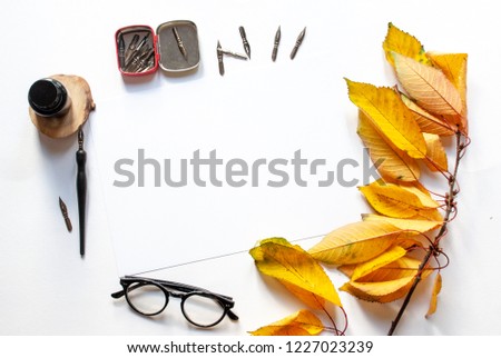 Autumn twig with leaves ,black ink and ink bottle, white sheet mockup and ink pen on a white background; top view, flat lay; overhead view