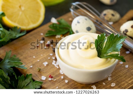 Mayonnaise Sauce close-up. Homemade mayonnaise sauce in a white bowl on black stone or concrete background. Royalty-Free Stock Photo #1227026263