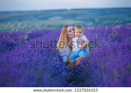 Happy mom with cute son on lavender background. Beautiful woman and boy in meadow field. Lavender landscape with lady and kid enjoying aroma and vivid colors. Family picture in colorful lavender view.