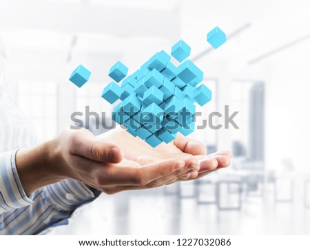 Close of businessman hand holding cube figure as symbol of innovation. 3D rendering