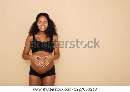 Pregnant woman holding hands on her belly making a heart symbol Royalty-Free Stock Photo #1227050269