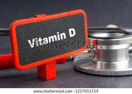 Blackboard with word VITAMIN D and stethoscope on dark background with selective focus and crop fragment. Health and medical concept