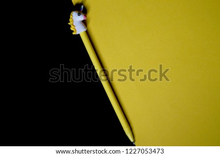 
Pen with a cap in the shape of a unicorn on a yellow-black background