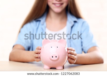 Young girl with pink piggybank sitting at table