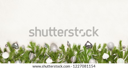 Christmas or New Year background: fir tree branches, silver glass balls, decoration  on a white plaster background
