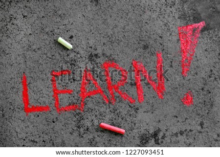 Colorful chalk drawing on asphalt: Red word LEARN 