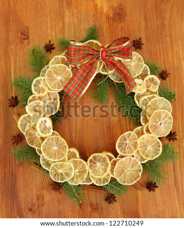 christmas wreath of dried lemons with fir tree and bow, on wooden background
