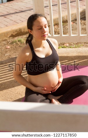 Sporty pregnant woman at lagoon park building. Meditation moment. Cancun, Mexico.
