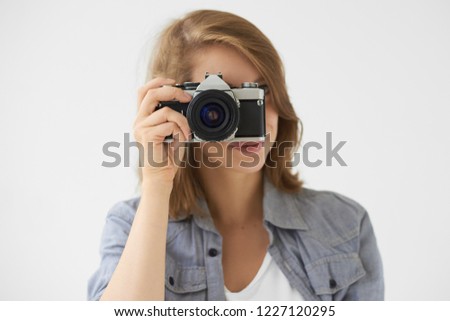 People, lifestyle and technology concept. Studio shot of stylish girl holding roll film camera at her face, taking picture of you. Young woman photographer using vintage device to take photo