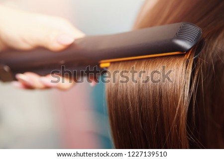 Hair iron straightening beauty care salon spa. Royalty-Free Stock Photo #1227139510