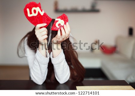 Beautiful brunette holding two parts of broken heart Royalty-Free Stock Photo #122714101
