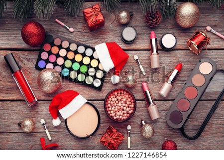 Makeup cosmetics with christmas baubles and santa hat on wooden table