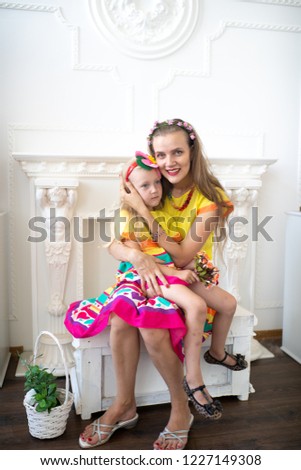 Style summer family look. Mom and daughter love. Take care of the child and ensure a happy childhood. Fun holidays. Bright yellow pink dress and floral decorations. White professional studio banner