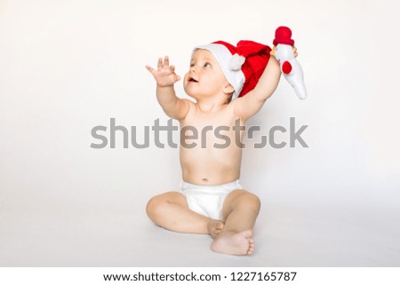 Adorable child wearing red Christmas cap and holding a little snowman, isolated over white