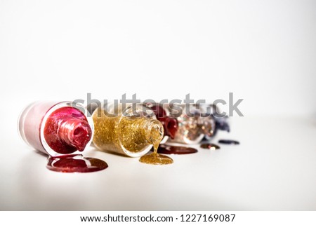 Nail polish flowing out of bottles isolated on white background