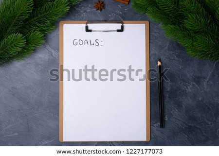 Personal goals concept. Blank paper with goals title and black pencil on grey table. Flat lay. Top view. New year concept. Free space. Copy space.