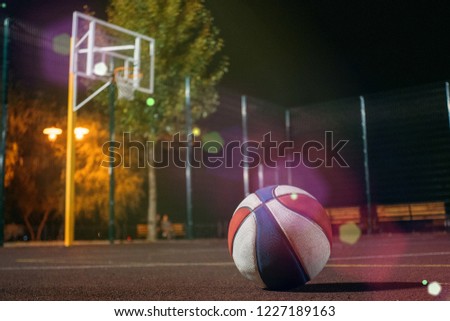 Colorfull basketball ball with basket and net on background on dusk red field with light glowing