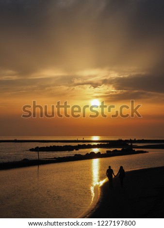 Perfect sunset by the sea. Leisure time. Sunlight and reflections in the water. Golden hour. People are walking, fishing in the evenings. Family Vacations. Holidays in Italy. Mediterranean Sea