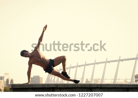 Sportsman doing arm balance on roof. Man exercising on white sky. Athlete showing handstand outdoors. Fitness and sport. Healthy lifestyle concept