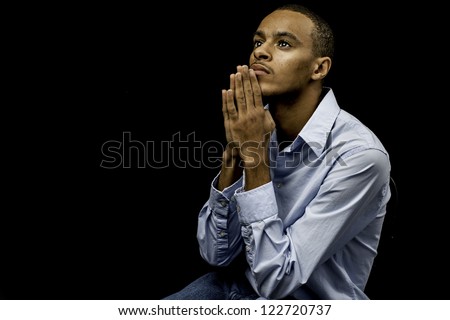 Nice isolation of a young african american black male praying with plenty of space for custom text