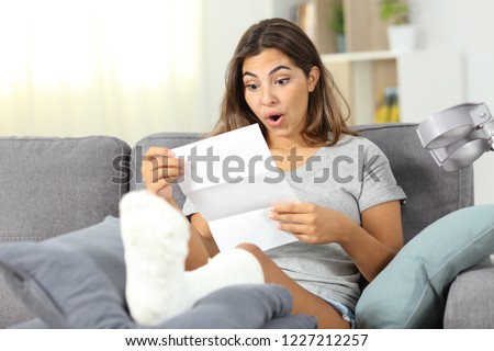 Surprised disabled girl reading notification  sitting on a couch in the living room at home Royalty-Free Stock Photo #1227212257