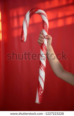Giant Candy Cane. A child holds a Giant Candy Cane with a Christmas Red background.