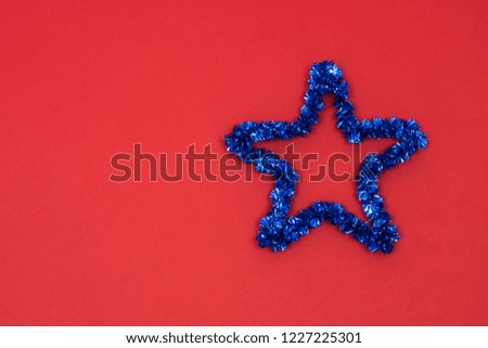 Decorative blue Christmas or New Year's toy star on red paper background. View from above with copy space.