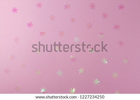A gentle transparent white snowflake on a light pink background. Flat Lay layout of New Year's decorations and confetti sequins.