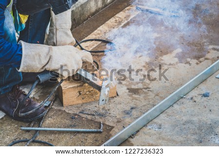 Worker wear mask and gloves for protection when arc welding for weld steel for make platform stand for install in building. Selective focus.