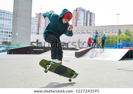 Full length portrait of modern teenager doing longboard stunts in extreme park, copy space
