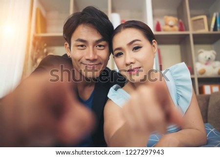 Young couple finger point to camera