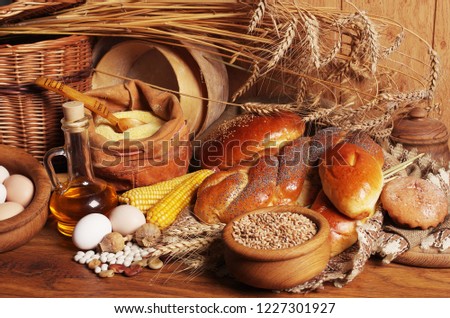 Baking and baking ingredients on a wooden table. Rolls, loaves, wheat grains, corn, flour, sunflower oil, eggs.
