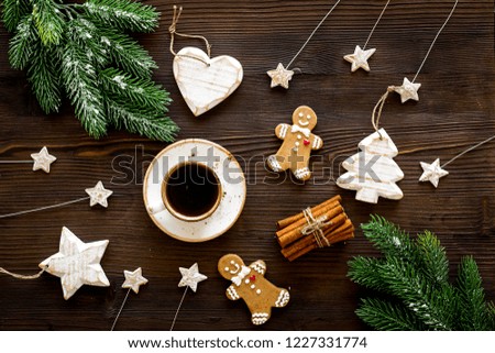 New Year composition with sweets. Gingerbread cookies in shape of man, spruce, star near coffee, spruce branch, festive decoration on black background top view