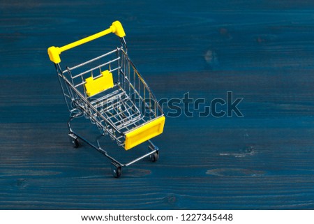 Toy shopping cart on blue wooden background