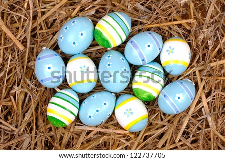closeup of colorful painted easter eggs hidden in a nest of straw