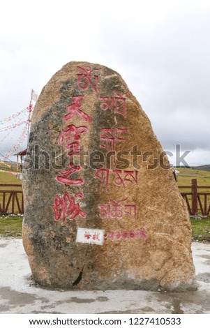A big stone road sign carved with Chinese and Tibetan which mean "City in the sky" , "Altitude  4300m", at a mountain top grass field , Litang, Ganzi, Sichuan, China, Sep 11th, 2018