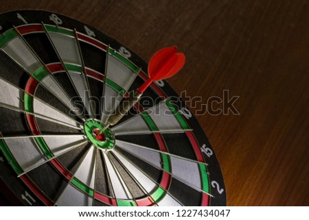 Red Dart hitting center Target, Right on target concept using dart in the bulls eye on dartboard business success concept fierce competition on stillife tone,