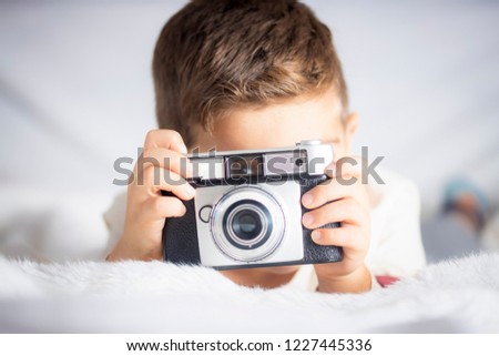 Beautiful boy with a photographing camera in the bed