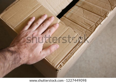 A hand on top of a cardboard box. Moving house concept image. 