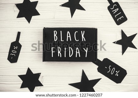 Black Friday big sale text sign, minimalistic flat lay. Special discount christmas offer. Stylish advertising message at black gift boxes, price tags on white rustic background. Christmas shopping
